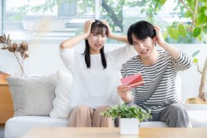通帳を持って頭を抱える夫婦