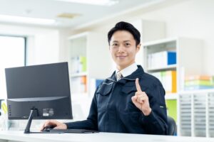 指を立てた作業着の男性