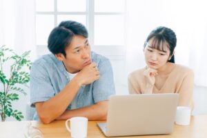 パソコンを見ながら悩む夫婦