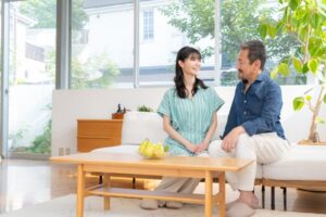 広い窓のあるリビングで談笑する夫婦