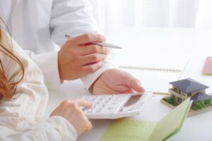 通帳・電卓・家の模型と夫婦の手