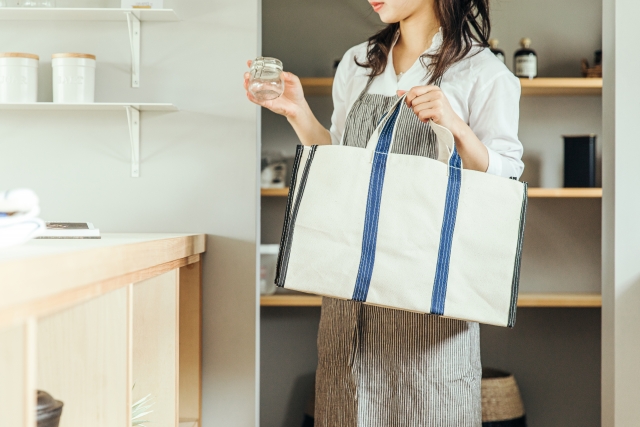 買い物袋を持ってパントリーをのぞく女性