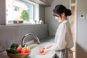 キッチンで野菜を洗う女性