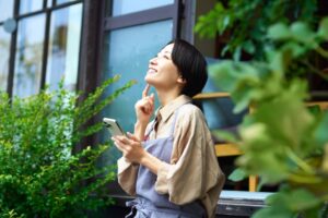 縁側で携帯を見ながら空を見上げる女性